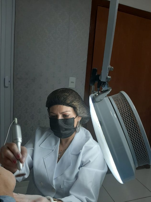 Elaine atendendo com lupa e micromotor